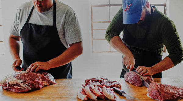 Butchers cutting beef at a wooden butcher block