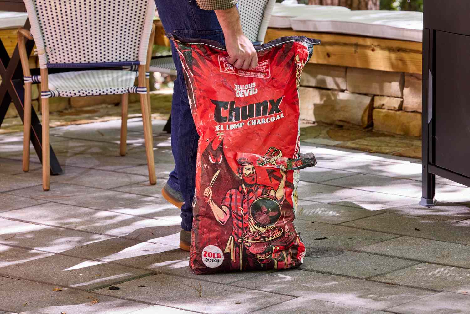 man carrying a bag of charcoal across a patio